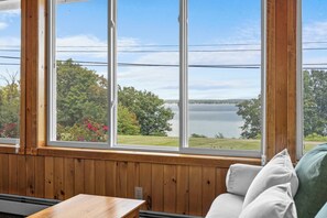 A room with a large window overlooking a lake and trees. - Wine Trail Retreat with Lake Access and Hot Tub (Geneva)