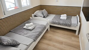 A room with two beds, wooden slats on the walls, a window, and a wall-mounted light fixture. - Villa 'Rocco-Salzwasserpool-Split' with Wi-Fi (Kaštel Gomilica)