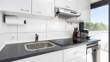 Una cocina moderna con armarios blancos, un lavamanos de acero inoxidable y un lavavajillas Bosch.