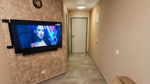 A hallway with a flat-screen TV mounted on a textured wall, a door at the end, and a sofa with a patterned pillow. - Villa 'Rocco-Salzwasserpool-Split' with Wi-Fi (Kaštel Gomilica)