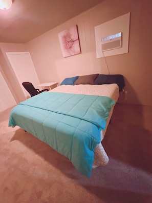 A bedroom with a bed, a chair, a desk, and a wall-mounted air conditioner. - Pet friendly/Fully fenced/3 bedroom house/King beds (Oklahoma City)