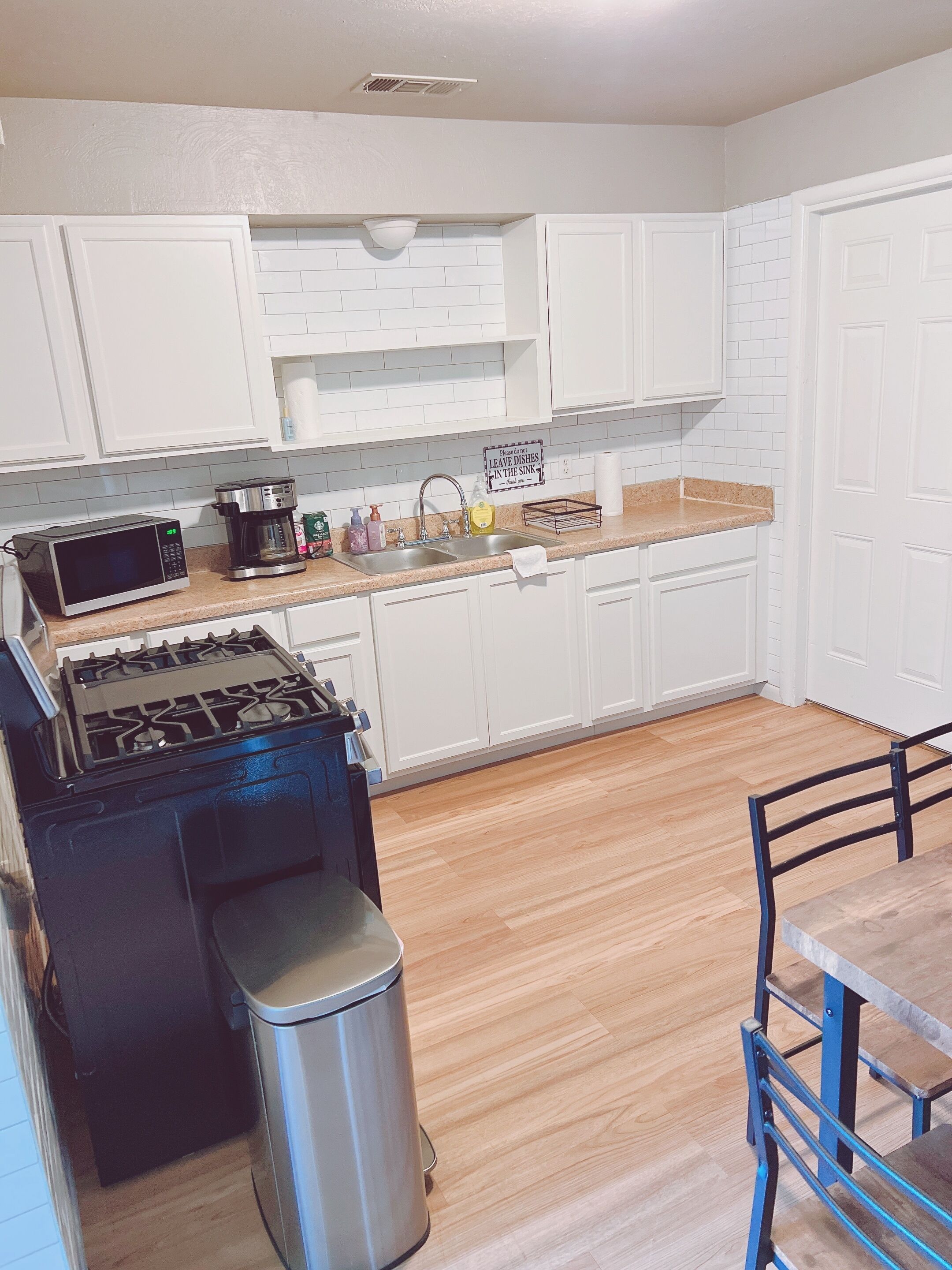 A kitchen with white cabinets, a stainless steel stove, a microwave, and a sink.