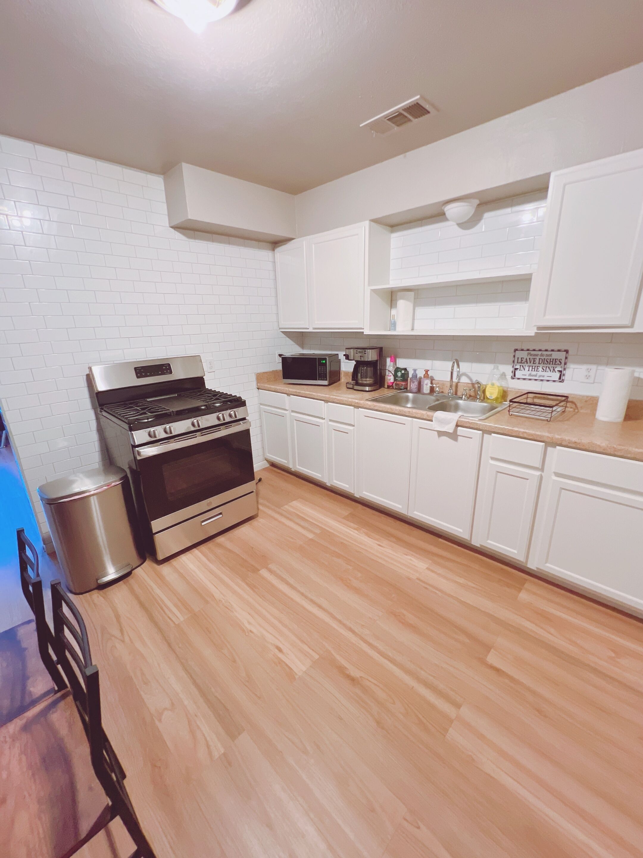 A kitchen with white cabinets, a stainless steel stove, a microwave, and a coffee maker.