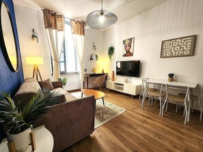 A modern living room with a sofa, coffee table, TV, and dining area. - City Center - 3 min from the Arènes - Scandinavian Decor (Nîmes)