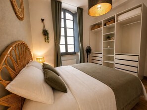 A bedroom with a bed, a fan, a window with curtains, and built-in storage. - Downtown - 3 minutes from the arenas - Scandinavian decor (Nîmes)