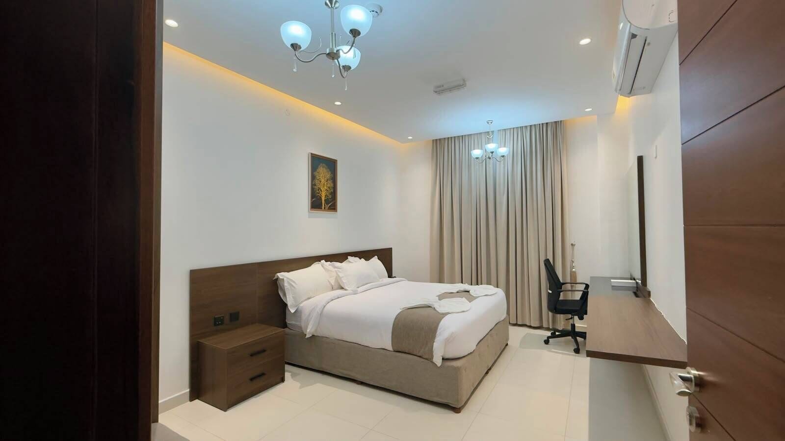 Un dormitorio moderno con cama, mesita de noche y escritorio con silla.