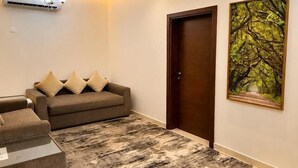 Um quarto com um sofá, uma porta e um quadro.