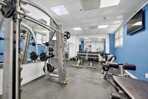 A gym with weightlifting equipment, mirrors, and a blue wall. - Fort Lauderdale Beach Escape - Pool, Tiki Bar & Beach Access (Fort Lauderdale)
