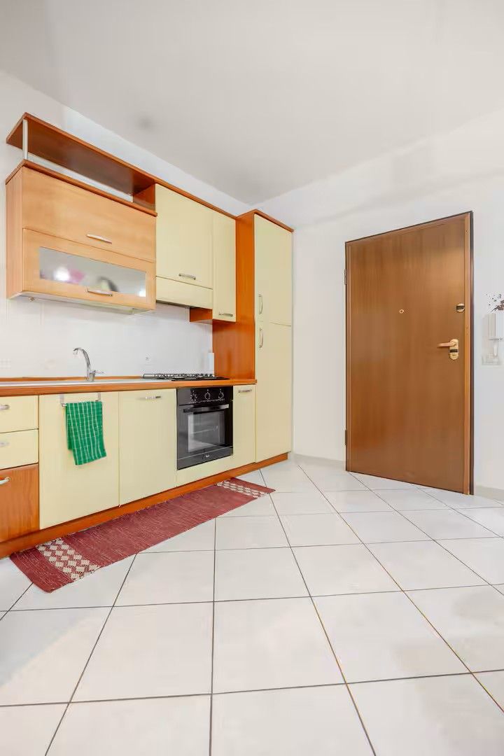 Una cocina compacta con horno empotrado, un mueble de madera y suelo de baldosas.