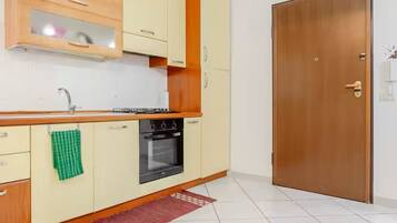 Una cocina compacta con horno empotrado, un mueble de madera y suelo de baldosas.