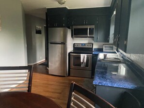 A kitchen with a refrigerator, oven, microwave, and a toaster.