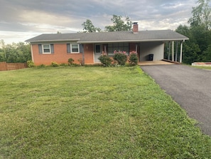 A two-story brick house with a front porch, a driveway, and a well-maintained lawn.