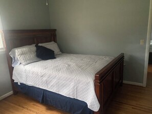 Une chambre à coucher avec un cadre de lit en bois, une couvre-lit blanche matelassée et une jupe de lit bleu foncé.