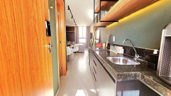 A kitchen with a double sink, wooden cabinets, and a dining area with a table and chairs. - Ancla del Sol by Hosppedar (Cabedelo)