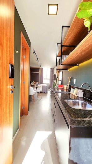 A modern kitchen with a black countertop, wooden cabinets, and a built-in shelf. - Ancla del Sol by Hosppedar (Cabedelo)