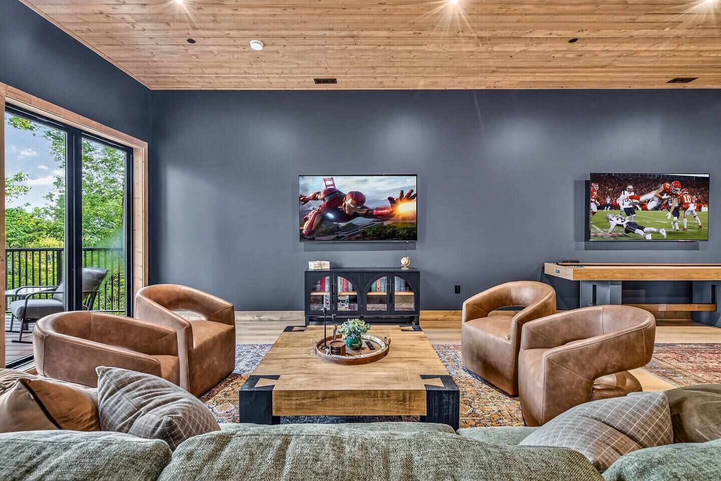 Ein modernes Wohnzimmer mit Ledersofas, einem Holztisch und einem großen Flachbildfernseher an der Wand.