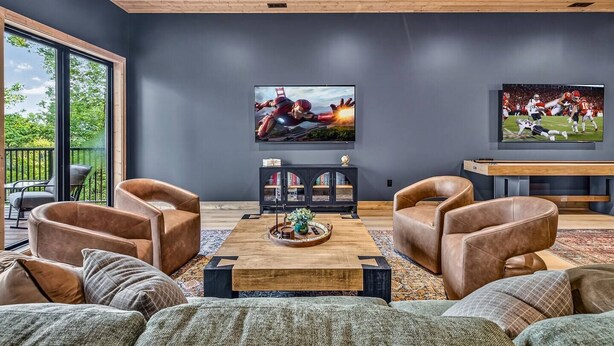 A modern living room with leather sofas, a wooden coffee table, and a large flat-screen TV mounted on the wall. - The Grotto • Indoor Pool • Rooftop • Sleeps 16 (Sevierville)