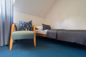 A small, single-bed room with a chair and a bedside table. - Holiday Home 'Ferienhof Homann Sauerland - LH 1' with Shared Terrace and Wi-Fi (Brilon)