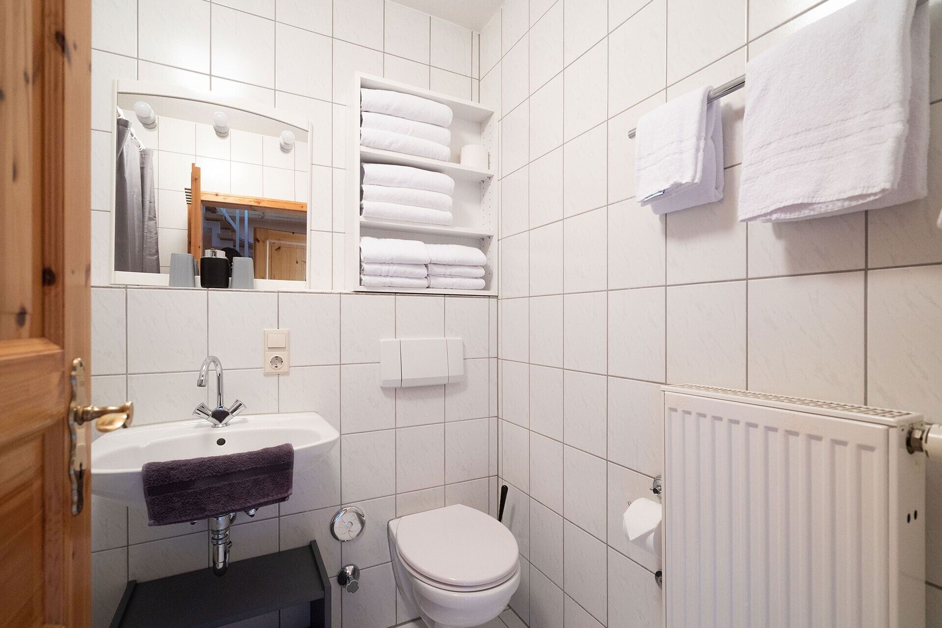 A bathroom with a white sink, a toilet, a mirror, and a towel rack.