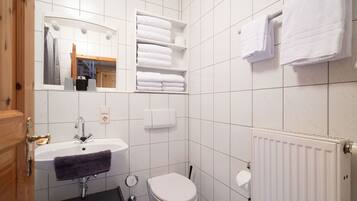A bathroom with a white sink, a toilet, a mirror, and a towel rack.
