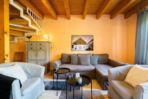 A cozy living room with a sofa, two armchairs, a coffee table, and a staircase. - Ferienhaus 'Ferienhof Homann Sauerland – LH 1' mit Gemeinschaftsterrasse und WLAN (Brilon)