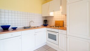 Eine Küche mit weißen Schränken, einer Holzausziehtafel, einer Spüle und einem Herd.