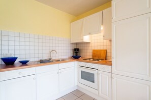 Eine Küche mit weißen Schränken, einer Holzausziehtafel, einer Spüle und einem Herd.