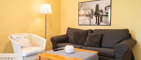 Una sala de estar con un sofá, una silla, una lámpara, una mesa de centro y un cuadro en la pared.
