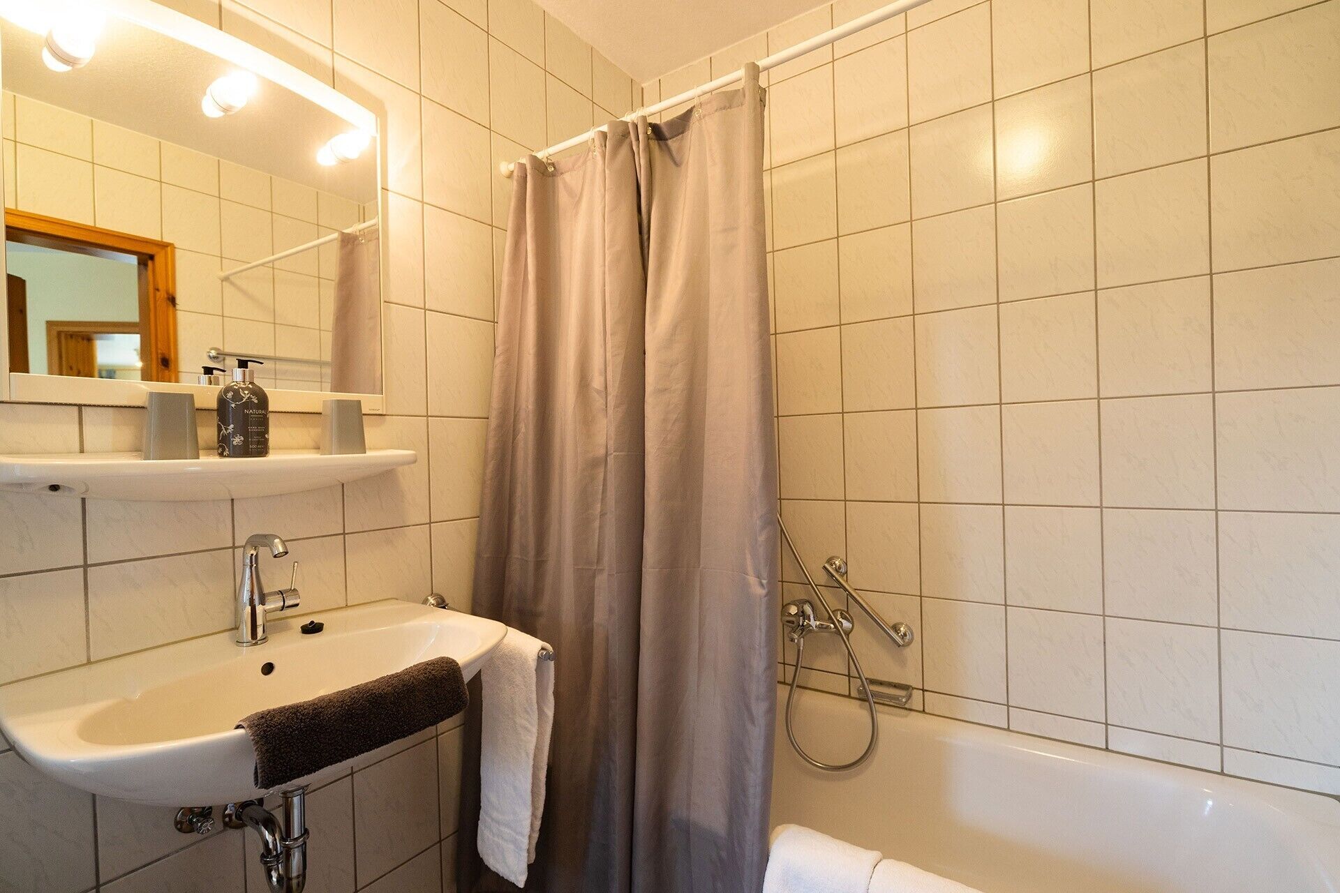 A bathroom with a sink, mirror, and shower.