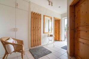 A room with a wicker chair, a small table with a candle, a mirror, and a wooden door. - Apartment 'Ferienhof Homann Sauerland – LH 4' with Balcony, Wi-Fi, Family Friendly (Brilon)