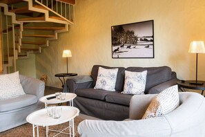 A living room with a grey sofa set, a white coffee table, and a staircase. - Ferienhaus 'Homann Sauerland – LH 7' mit gemeinsamer Terrasse und WLAN (Brilon)