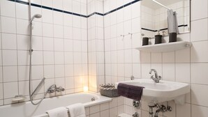Ett badrum med badkar, handfat, dusch och spegel.