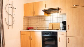 Eine kleine Küche mit Holzschränken, einem eingebauten Backofen und einer Kaffeemaschine.