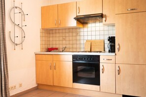 Una cocina compacta con armarios de madera, horno integrado y cafetera.