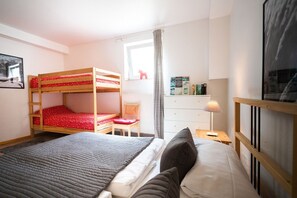Un dormitorio con literas, un escritorio, una silla, un aparador y una lámpara.