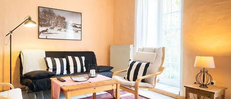 Un salon avec un canapé, un fauteuil, une table et un tableau accroché au mur.