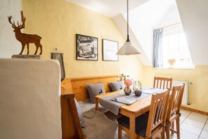 Una camera accogliente con una panca in legno, un tavolo da pranzo con sedie, un lampadario e quadri appesi alle pareti.