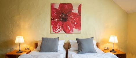 A hotel room with two beds, a large red floral artwork on the wall, and two bedside lamps.