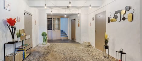 A hallway with a stone floor, a staircase, and a wall with abstract art.