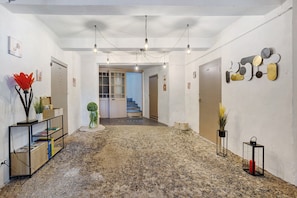 A hallway with a stone floor, a staircase, and a wall with abstract art.