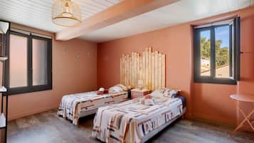 Una habitación con dos camas, un cabecero de madera, una mesita pequeña y una ventana.