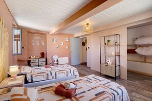 Un dormitorio con dos camas, un armario, un espejo y una mesita de noche con una lámpara.
