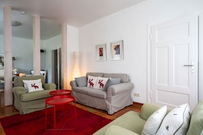 Ein Wohnzimmer mit einer Couch, zwei Sesseln, einem roten Teppich und einer Tür.