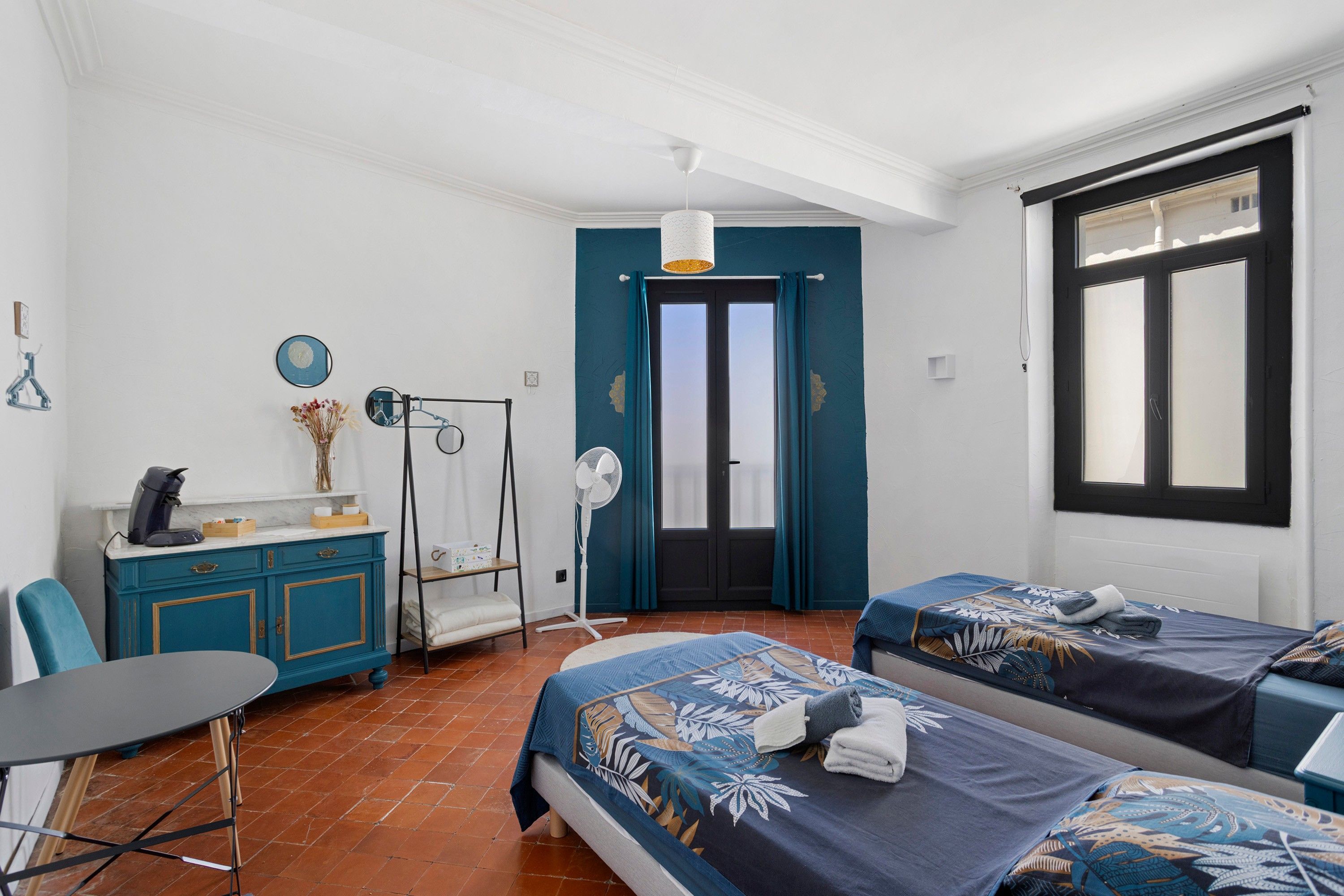 Habitació d'hotel amb dos llits, escriptori, cadira, armari i finestra amb vistes.