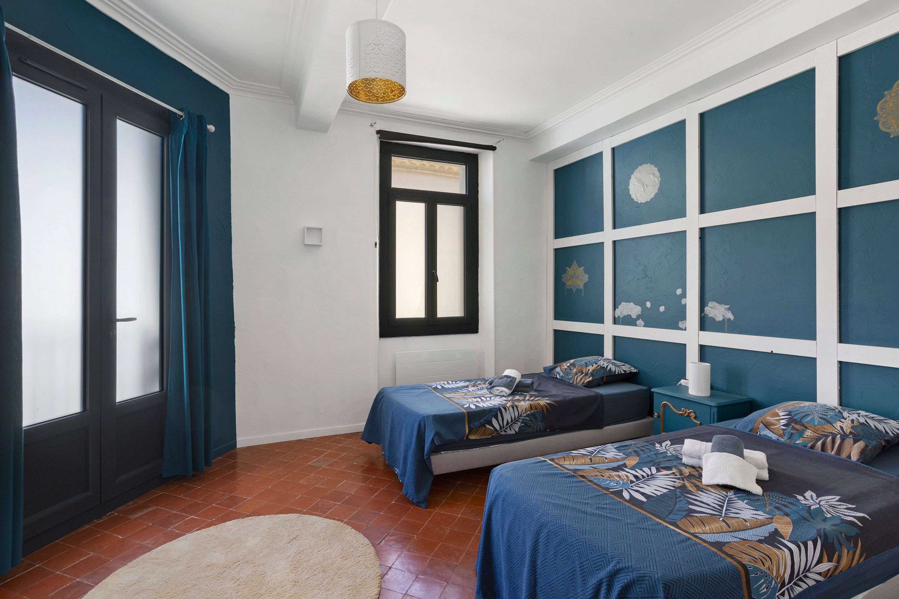 A bedroom with two beds, a window, and a door.