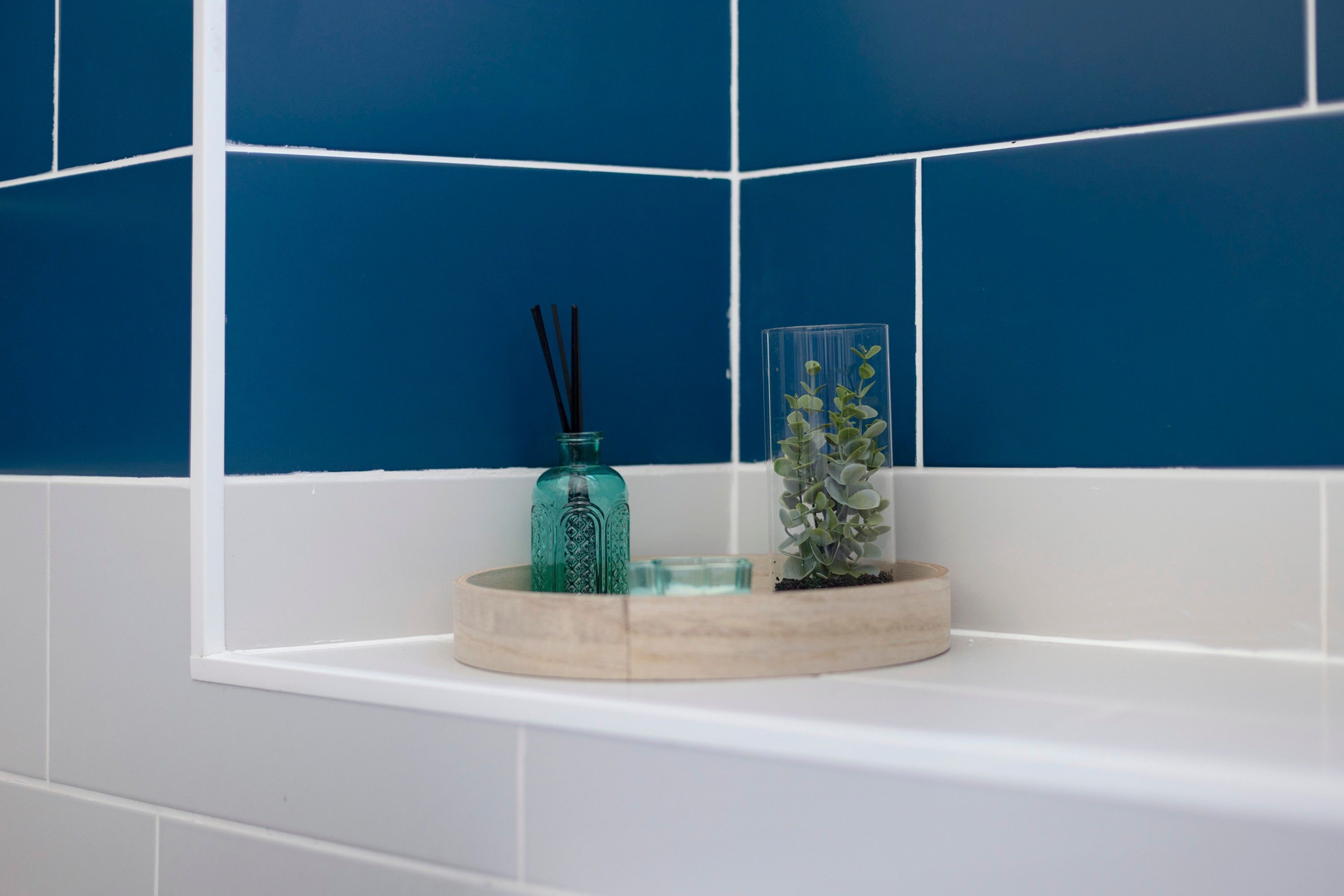 Um banheiro com azulejos azuis e uma banheira branca.