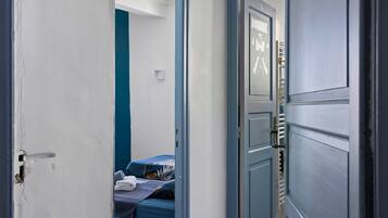 Una habitació amb un llit, una porta i una paret amb un interruptor de llum.