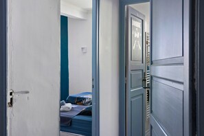 Una habitación con una cama, una puerta y una pared con un interruptor de luz.