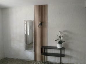 A room with a vertical panel, a small table with a potted plant, and a door leading to another room.