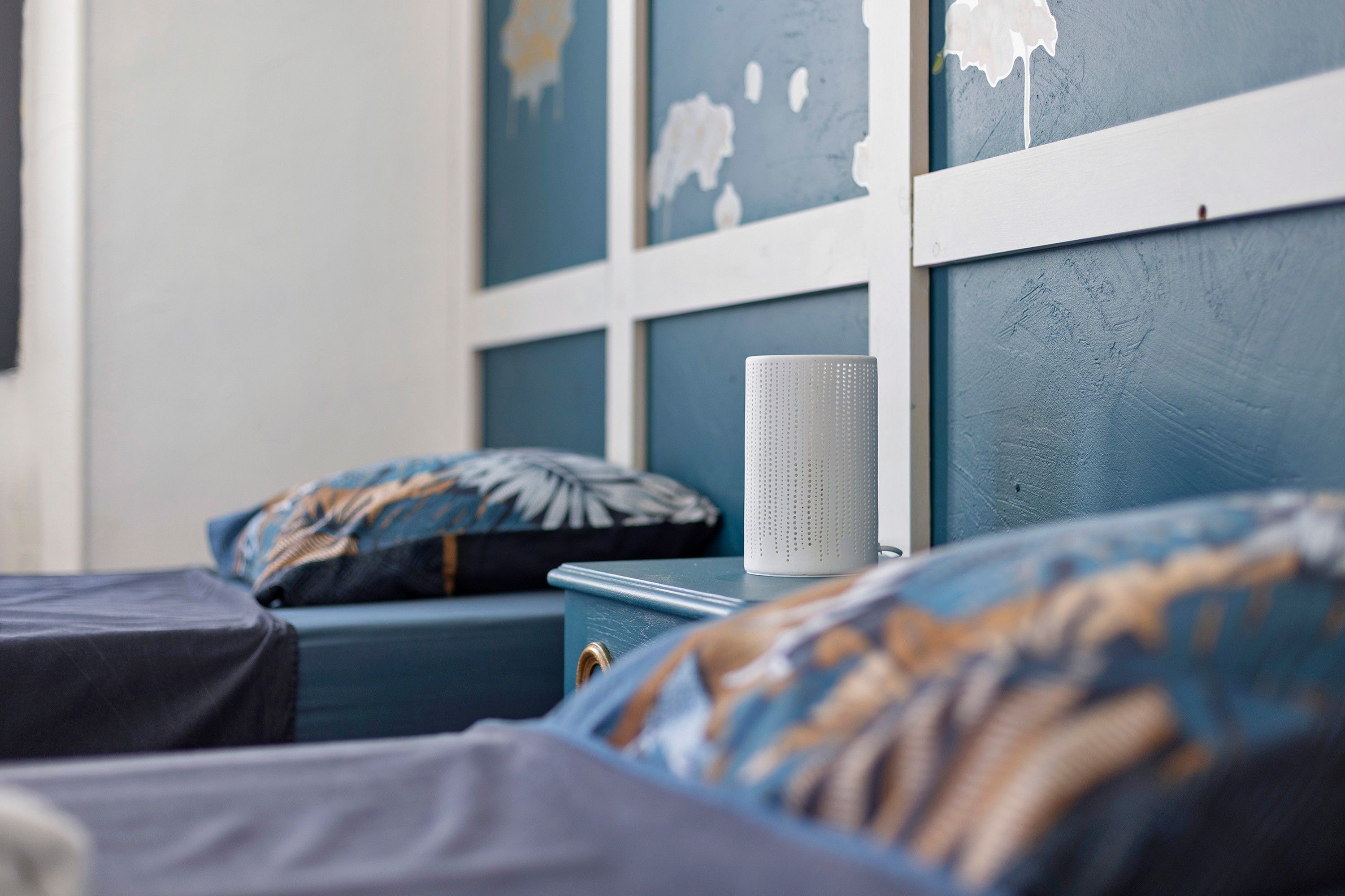 Une chambre à coucher avec un lit, une table de chevet et un haut-parleur fixé au mur.